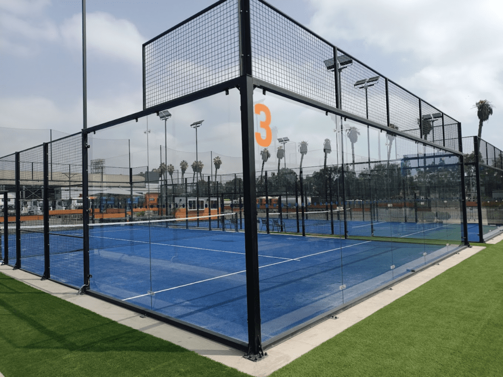 Outdoor padel court with blue turf and glass walls